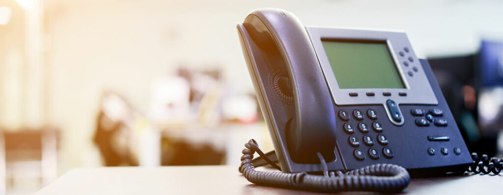 Schwarzes Telefon mit Schnur und großem Display zu einer Telefonanlage gehörend.